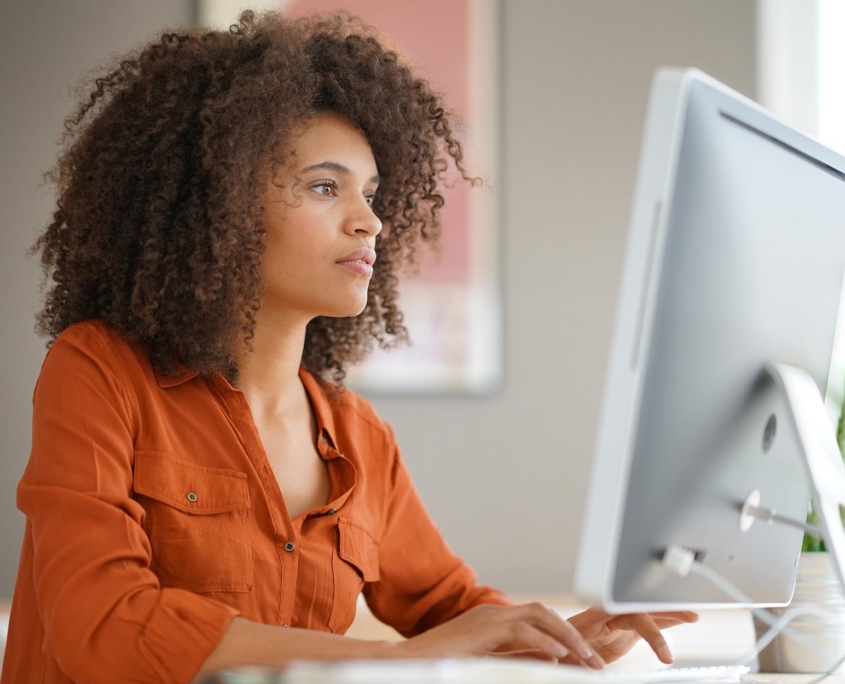 Side view of a focused woman looking at a monitor