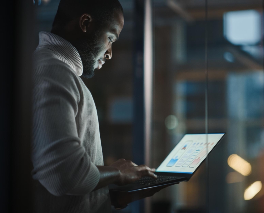 Side view of a man in a dark room using a computer