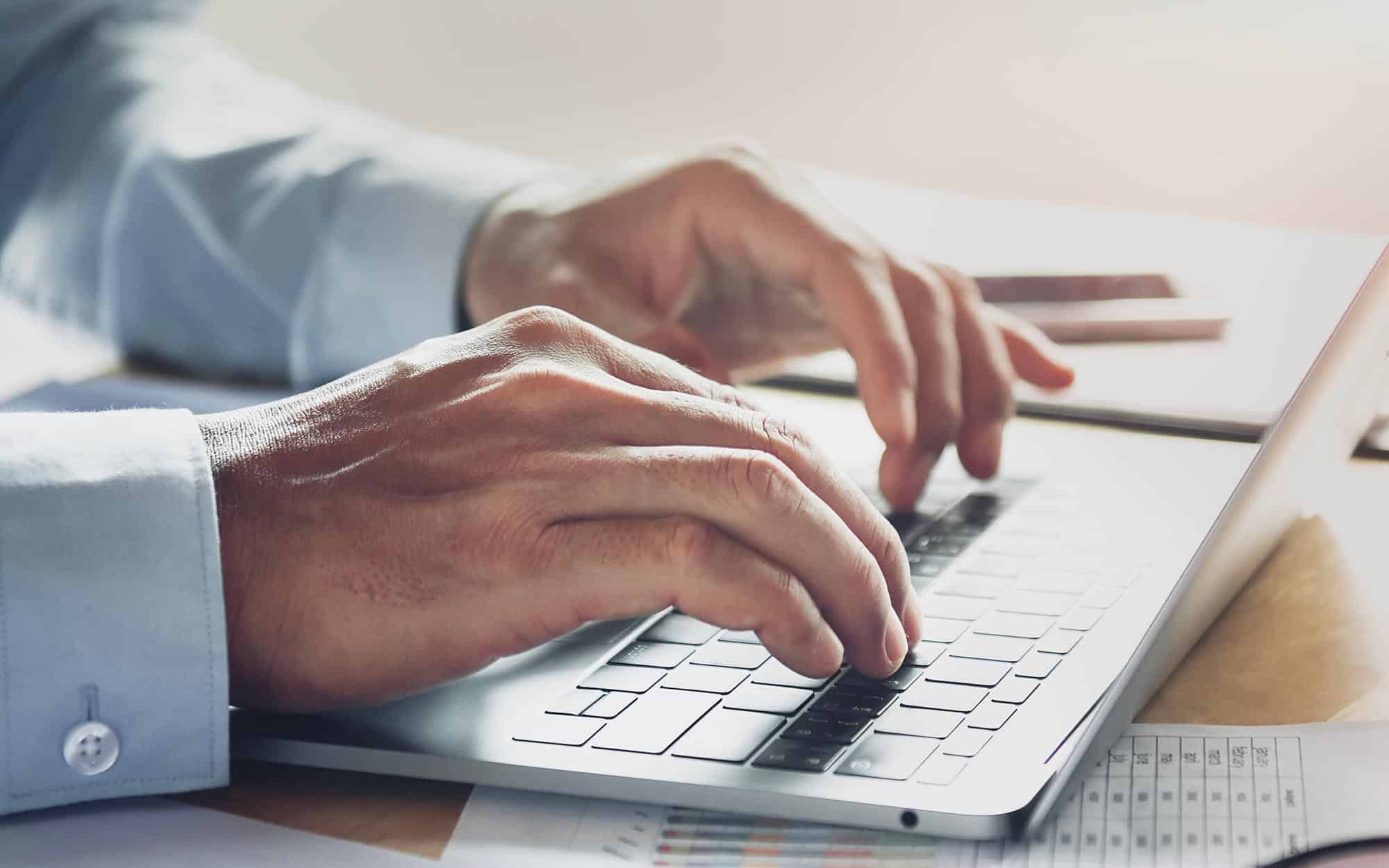 Side view of a pair of hands typing on a keyboard