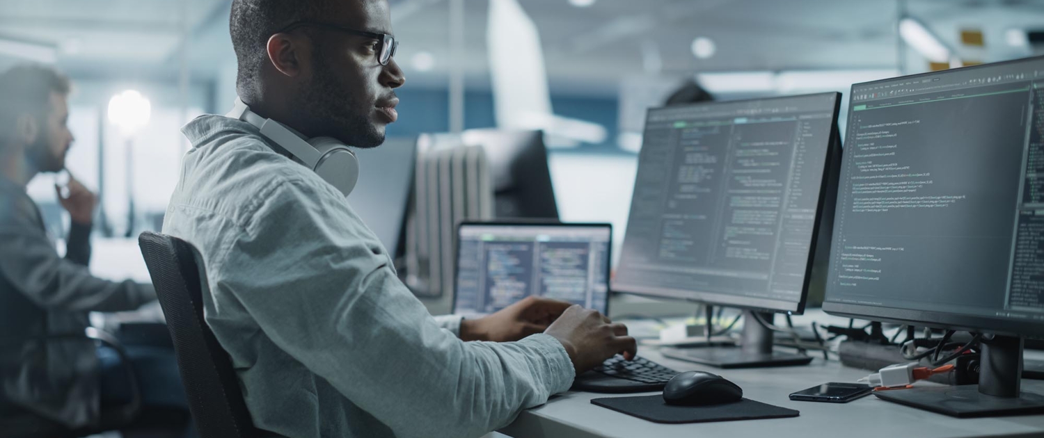 Side view of cybersecurity professional working on computer screens