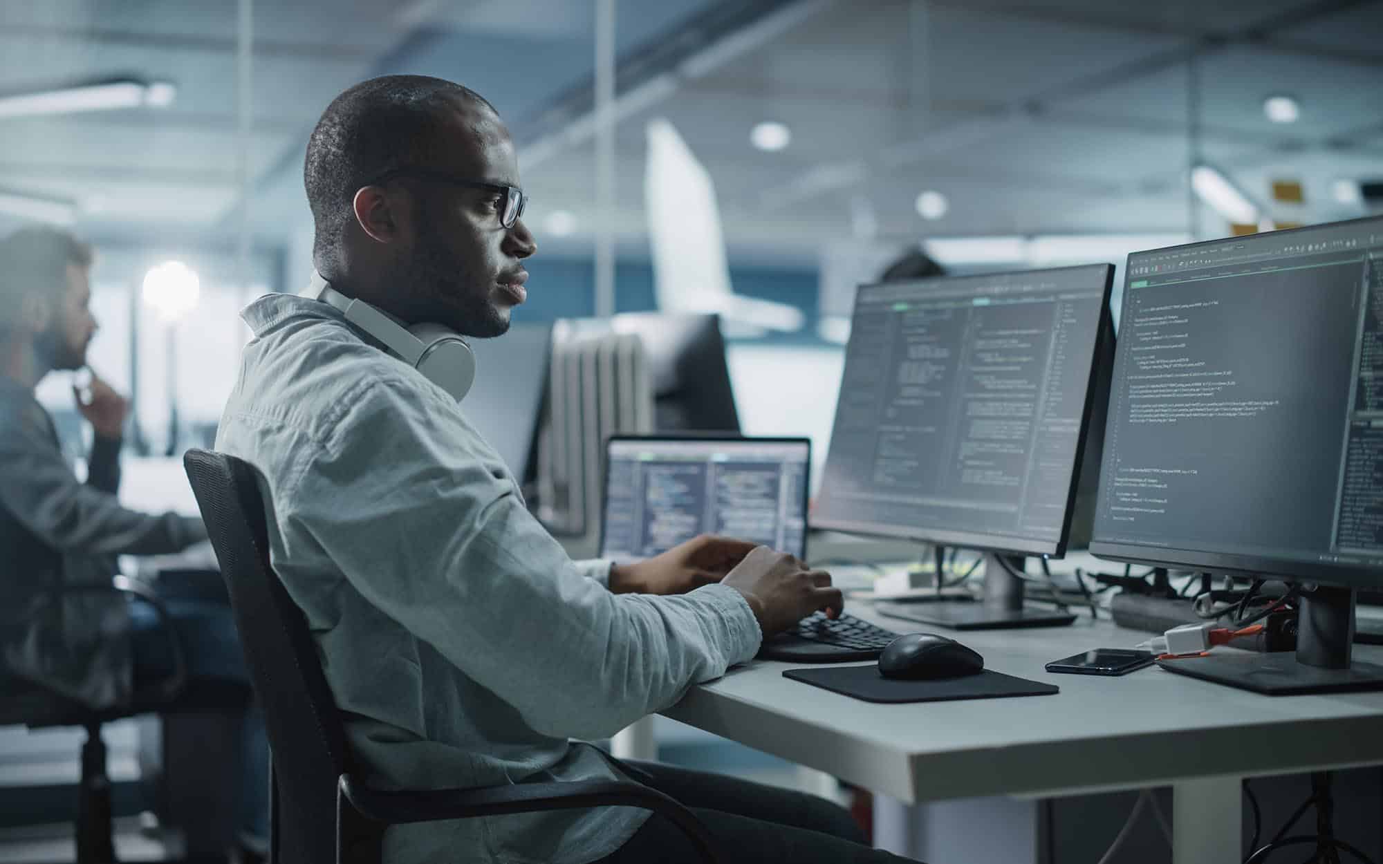 Side view of cybersecurity professional working on computer screens