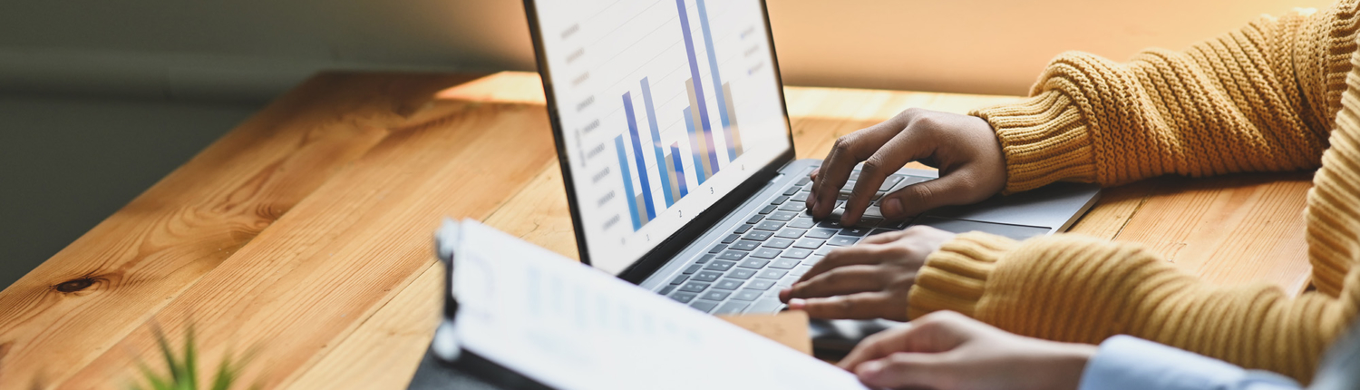 Side view of two people working together on laptop looking at financial documents