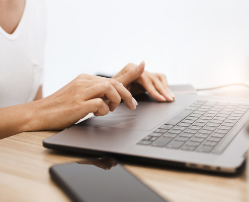 Side view, woman with manicured hands using laptop keyboard