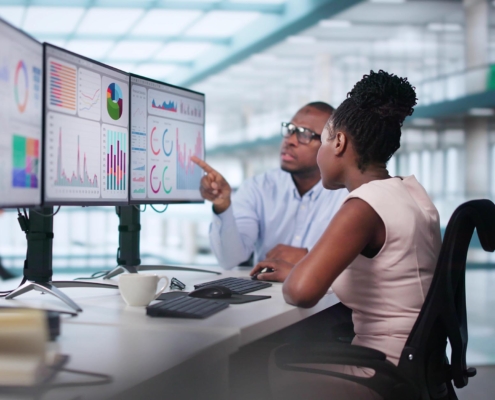 Two workers looking at data on computers