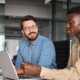 Two workers using laptops in office