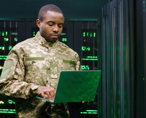 person in the military working on laptop in server room