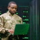 person in the military working on laptop in server room