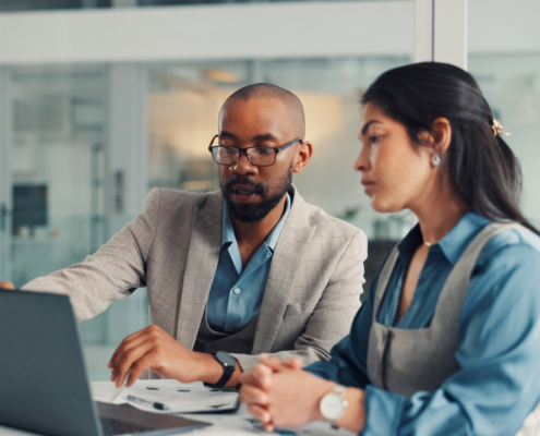 Business workers looking at information on laptop in office