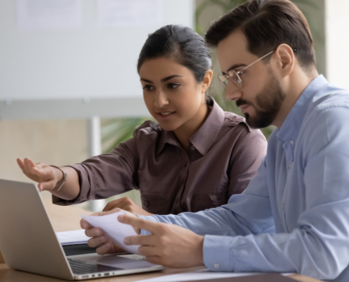 Two people at work using laptop